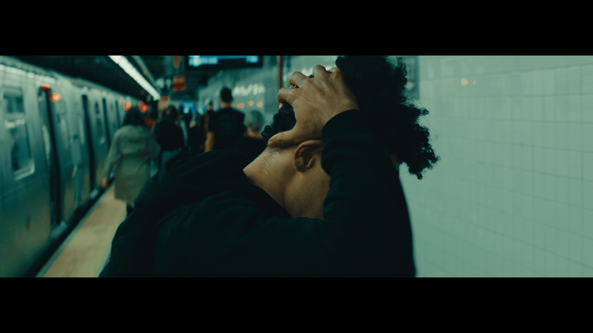 A man gripping his head on a New York City subway platform