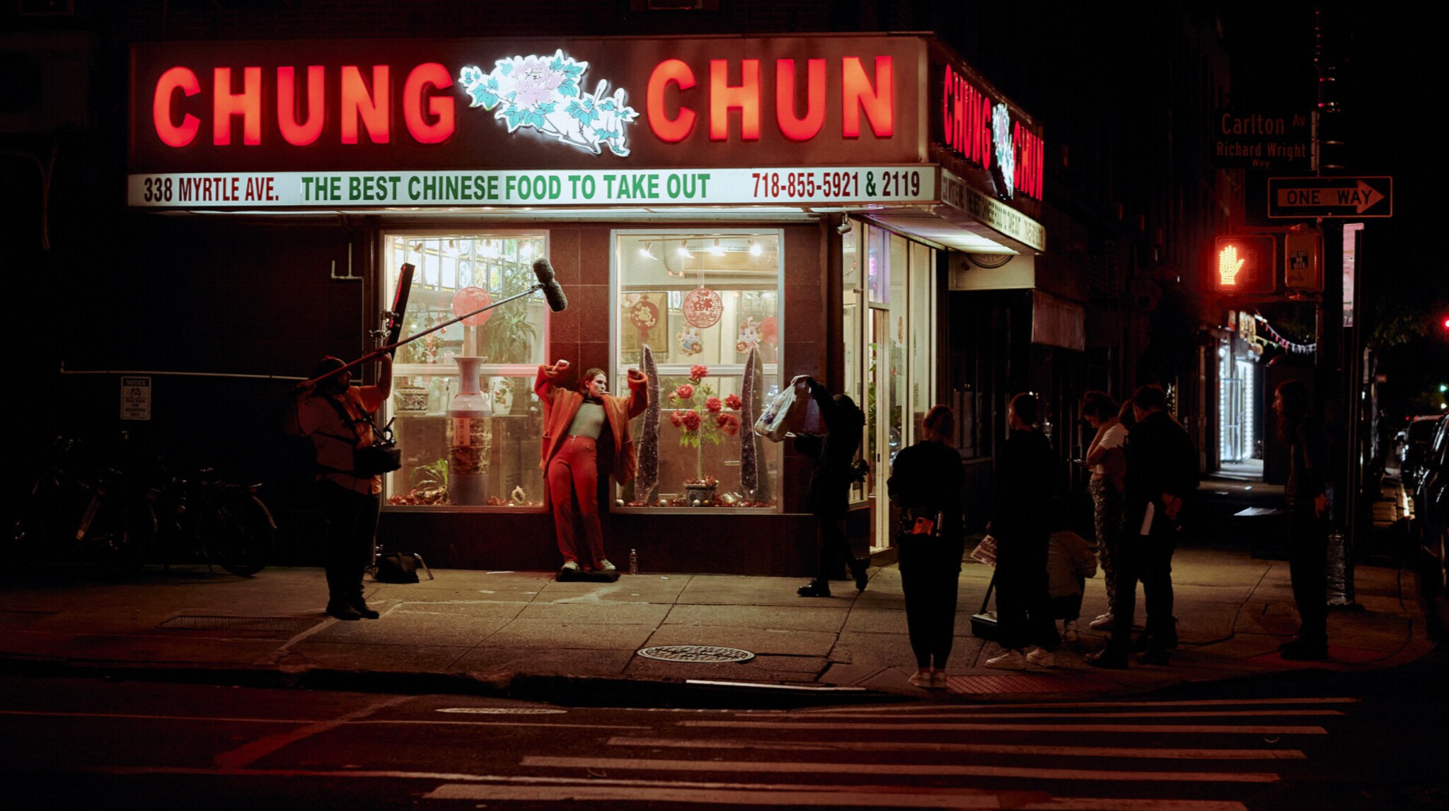A full film crew shooting a night exterior outside a New York City storefront