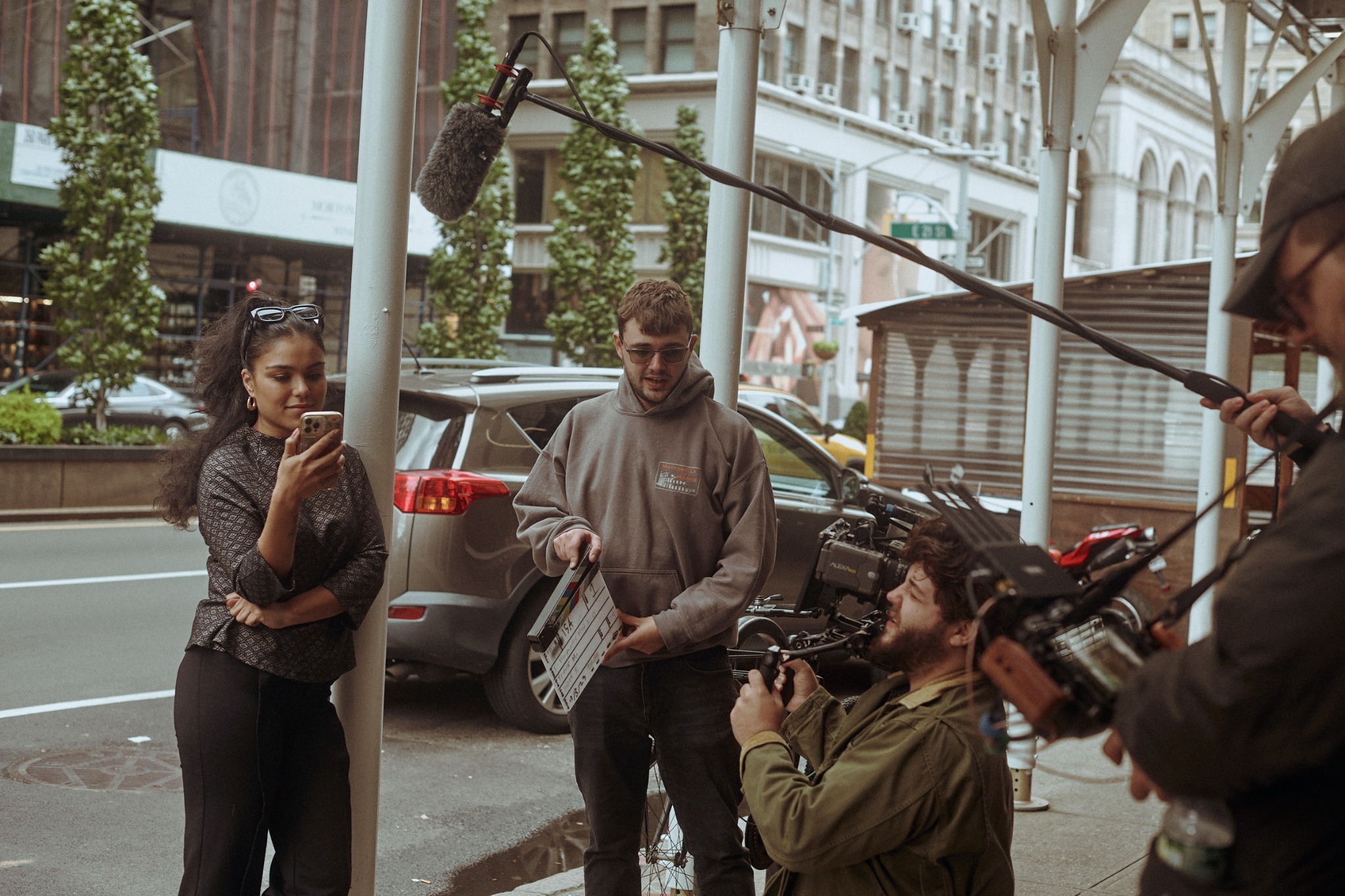 Actor and film crew preparing a street scene with camera and boom microphone